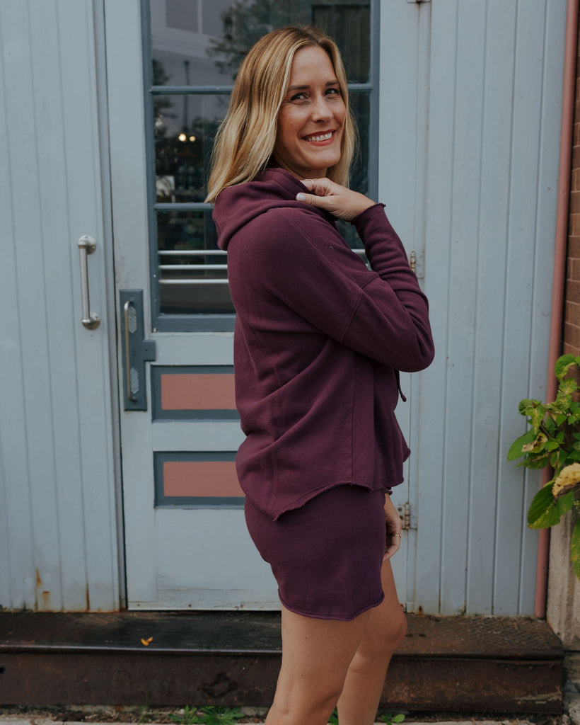 Woman wearing a purple outfit standing in front of a door.