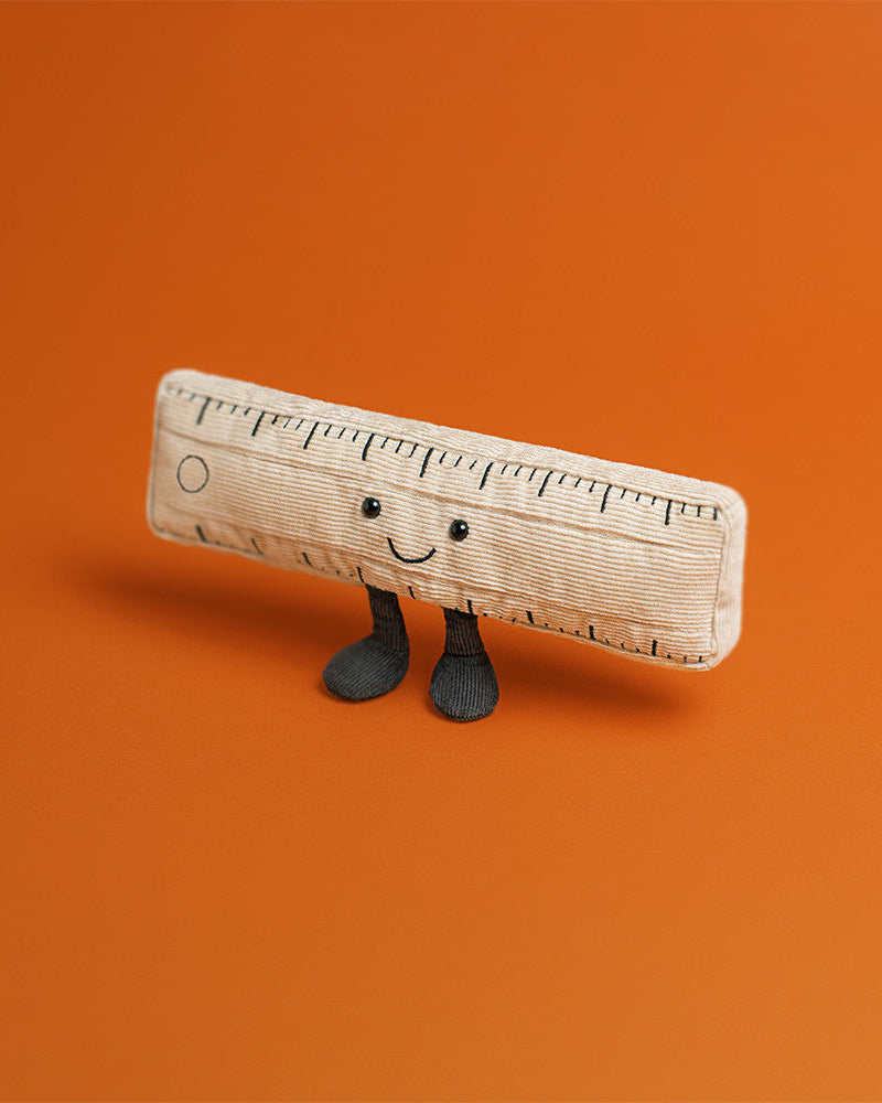Toy ruler with a smiley face and legs on an orange background