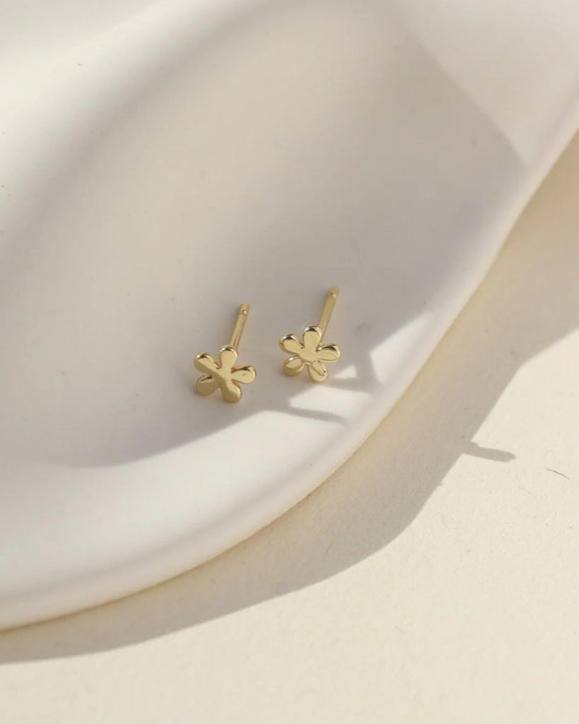 Gold four-leaf clover earrings on a white background