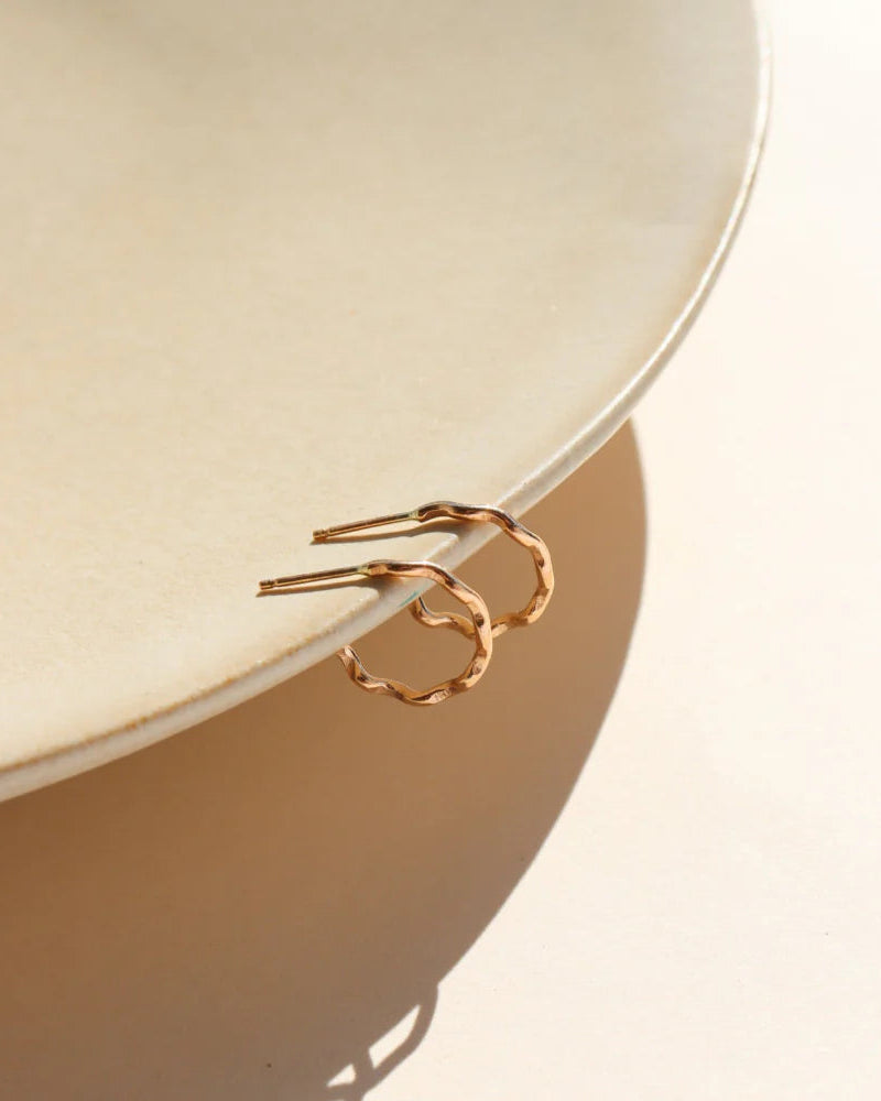 Gold hoop earrings on a beige ceramic plate