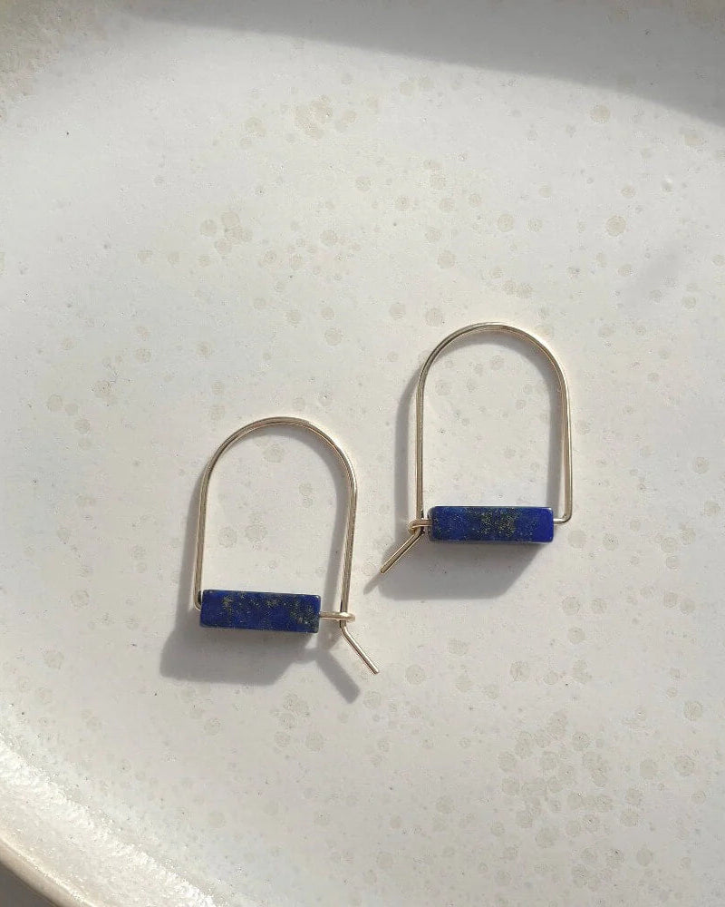 Pair of earrings with blue stones on a textured white surface