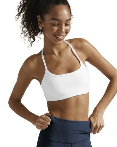 Woman wearing a white sports bra and navy leggings on a plain background