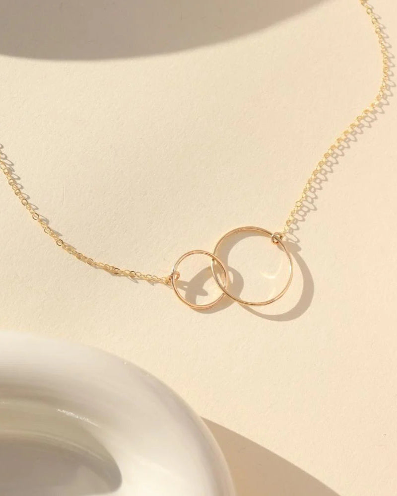 Gold necklace with interlocking rings on a beige background