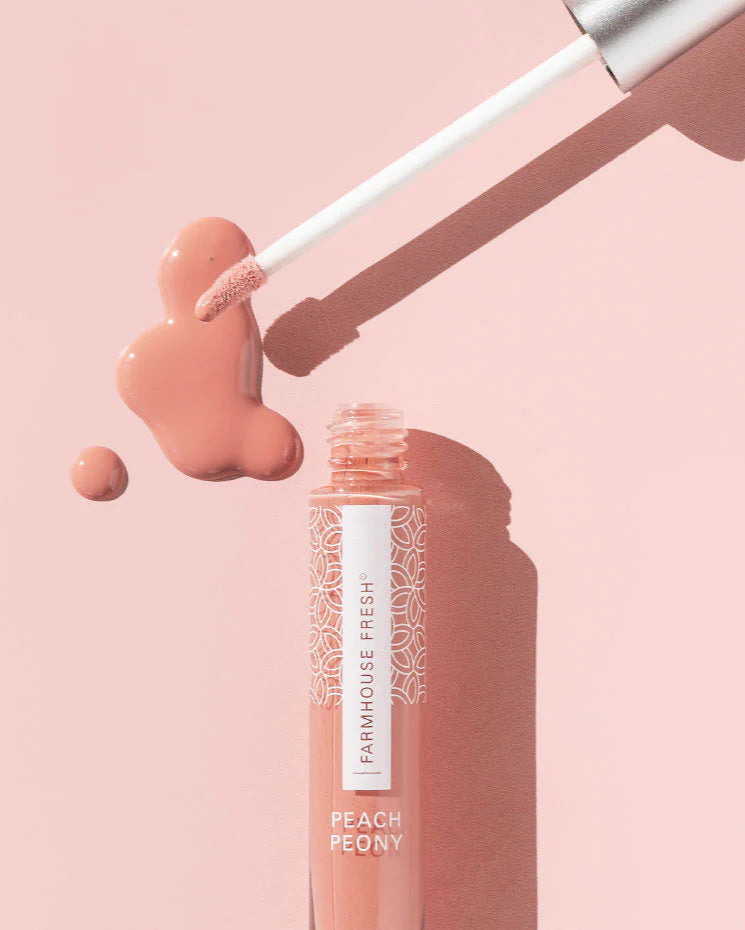 Lip gloss with applicator and 'Farmhouse Fresh' label on a pink background