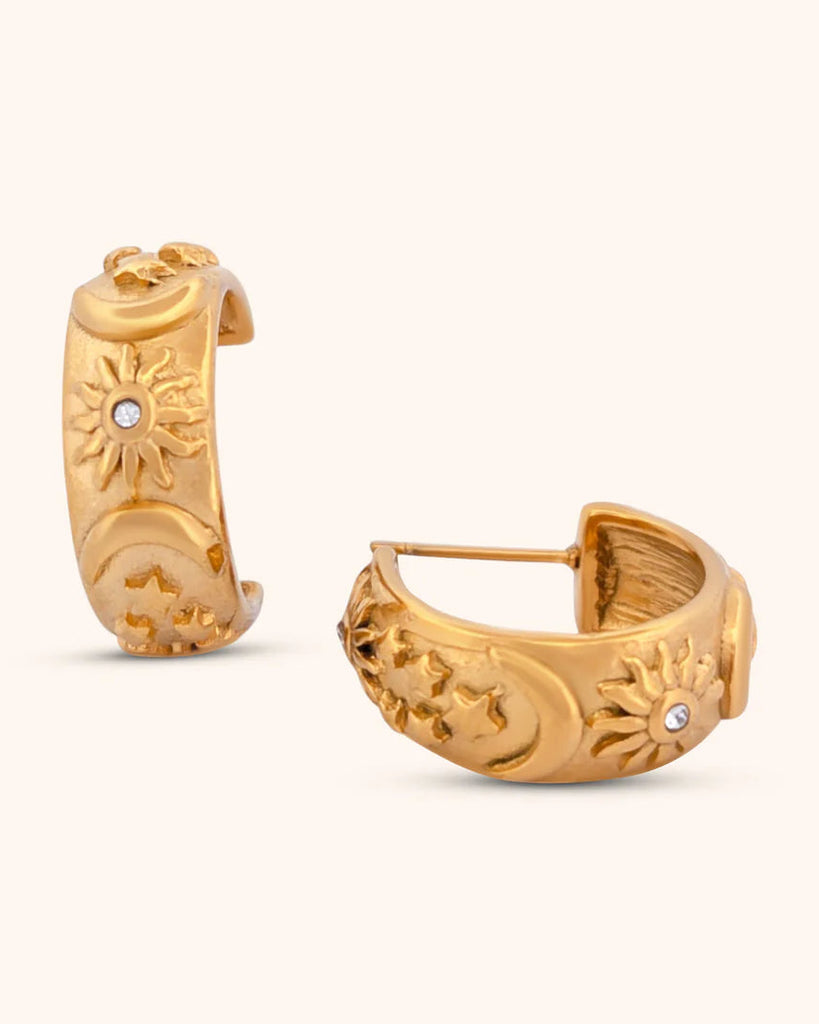 Gold hoop earrings with intricate designs on a white background