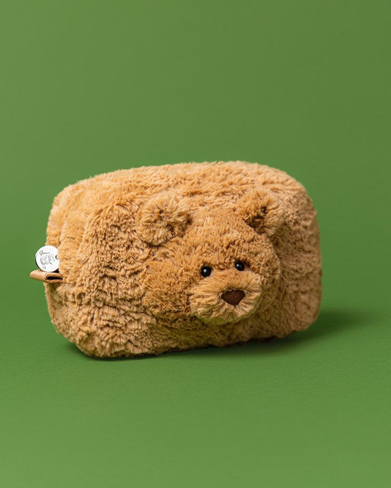 Plush bear-shaped pillow on a green background
