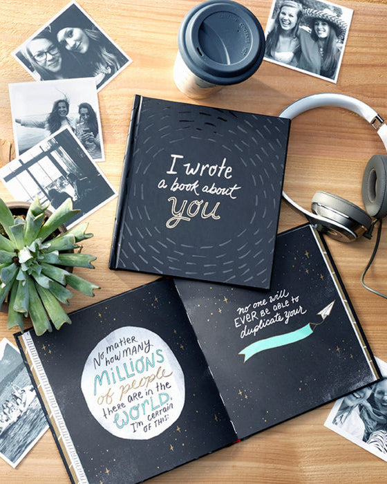 Two black books with white text on a wooden surface with photos, a plant, and headphones.