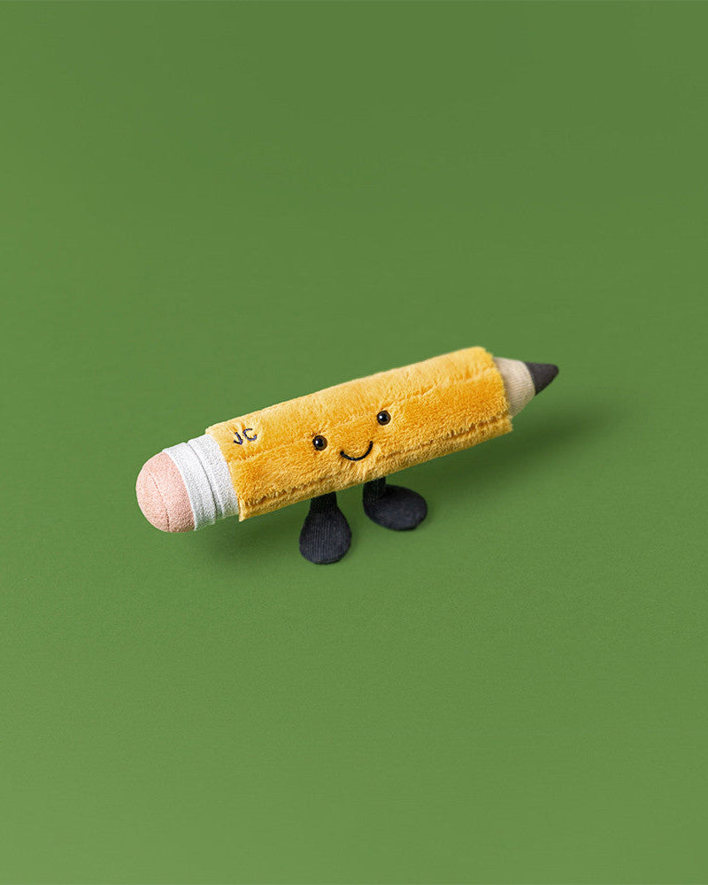 Plush toy pencil with a smiling face on a green background