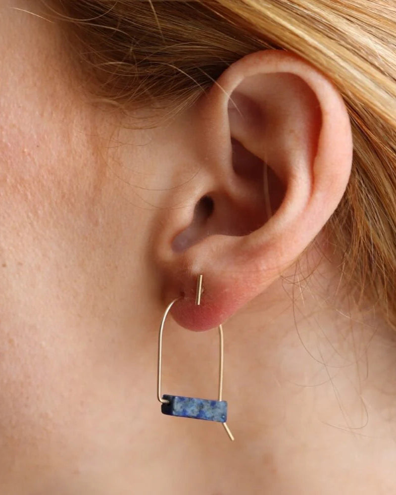 Close-up of an ear wearing a gold and blue earring.
