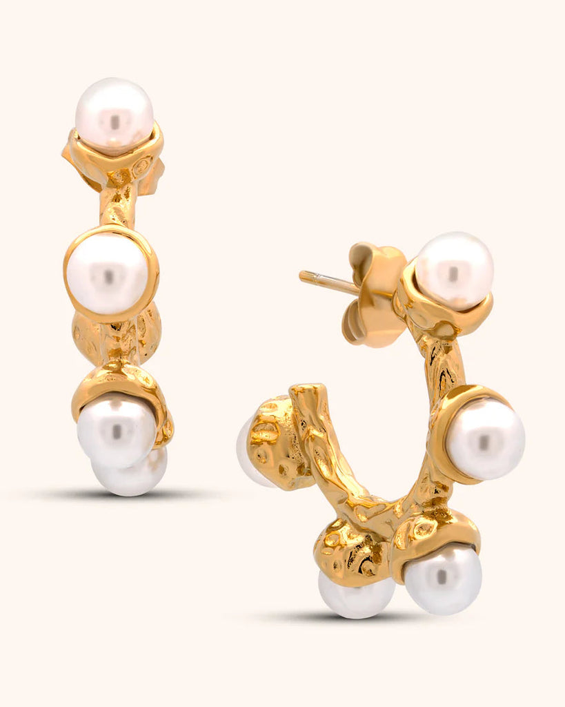 Gold earrings with pearl drops on a white background