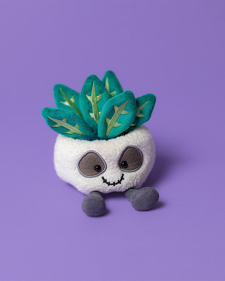 Plush toy with a white body and green leafy top on a purple background