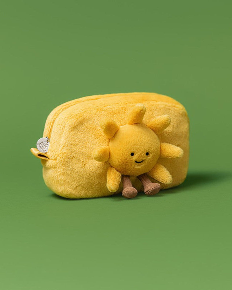 Yellow plush sun-shaped pouch with a smiling sun face on a green background