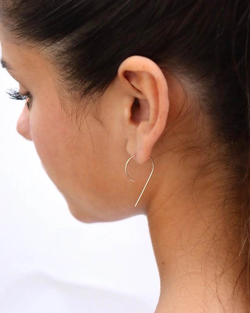 Close-up of a woman wearing a gold hoop earring on a white background
