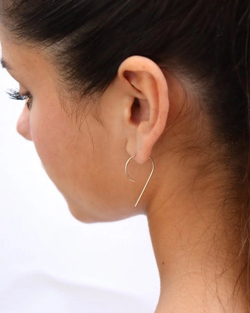 Close-up of a woman wearing a gold hoop earring on a white background