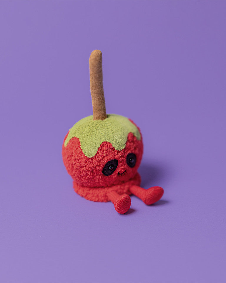 Crocheted candy apple toy on a purple background